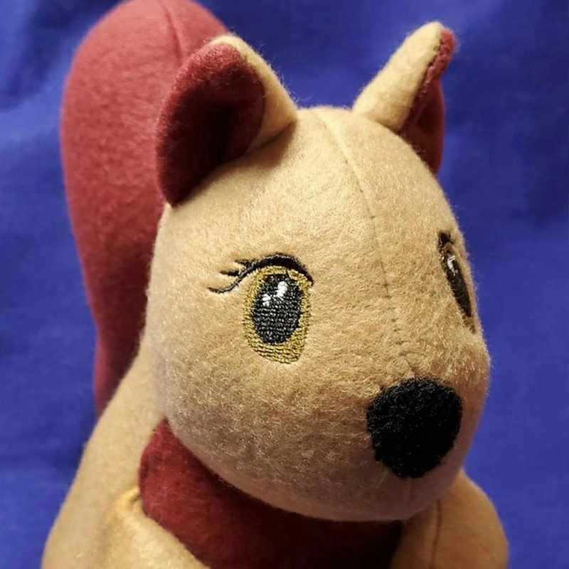 Close-up view of a soft plush toy with small embroidered eyes, gentle facial expression, and smooth short-pile fabric
