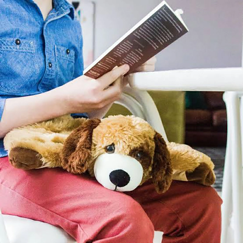 Adult holding a medium weighted plush naturally while reading in a chair