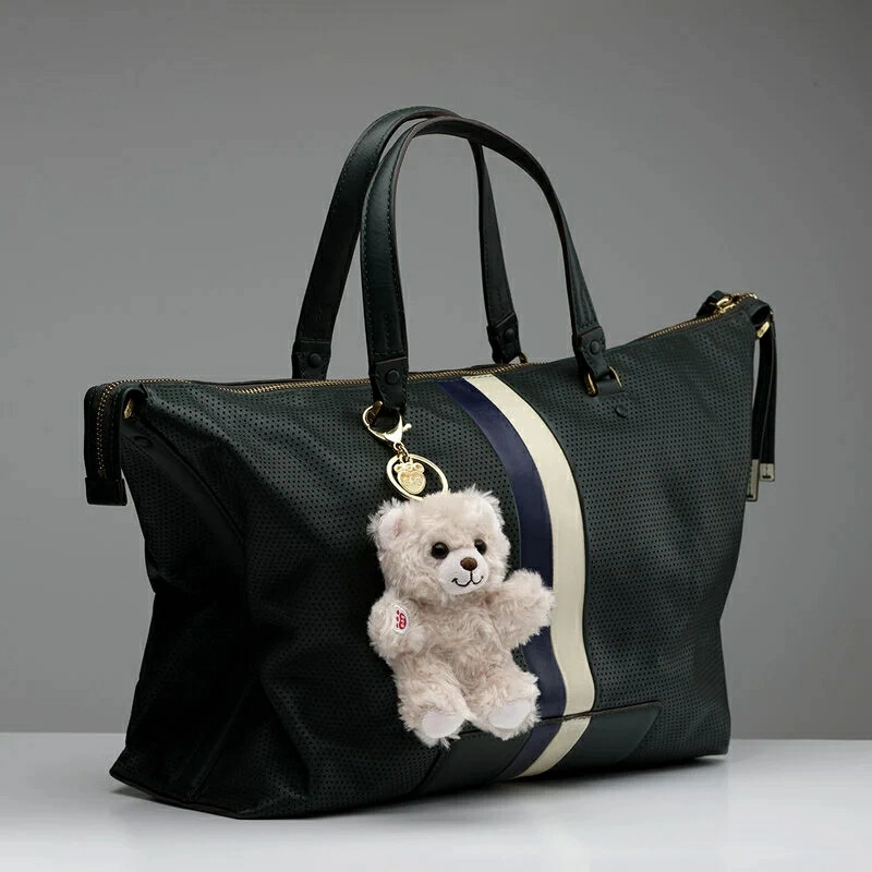 Small unbranded plush charm attached to a neutral tote bag as a personal accessory